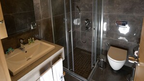 A modern bathroom with a glass-enclosed shower, a sink with a mirror, and a toilet. - Hotel Derin Ma Sorgun (Manavgat)