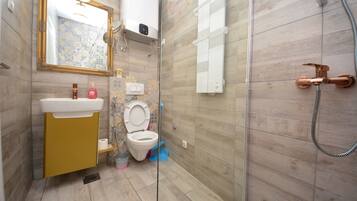 A bathroom with a toilet, sink, and shower.