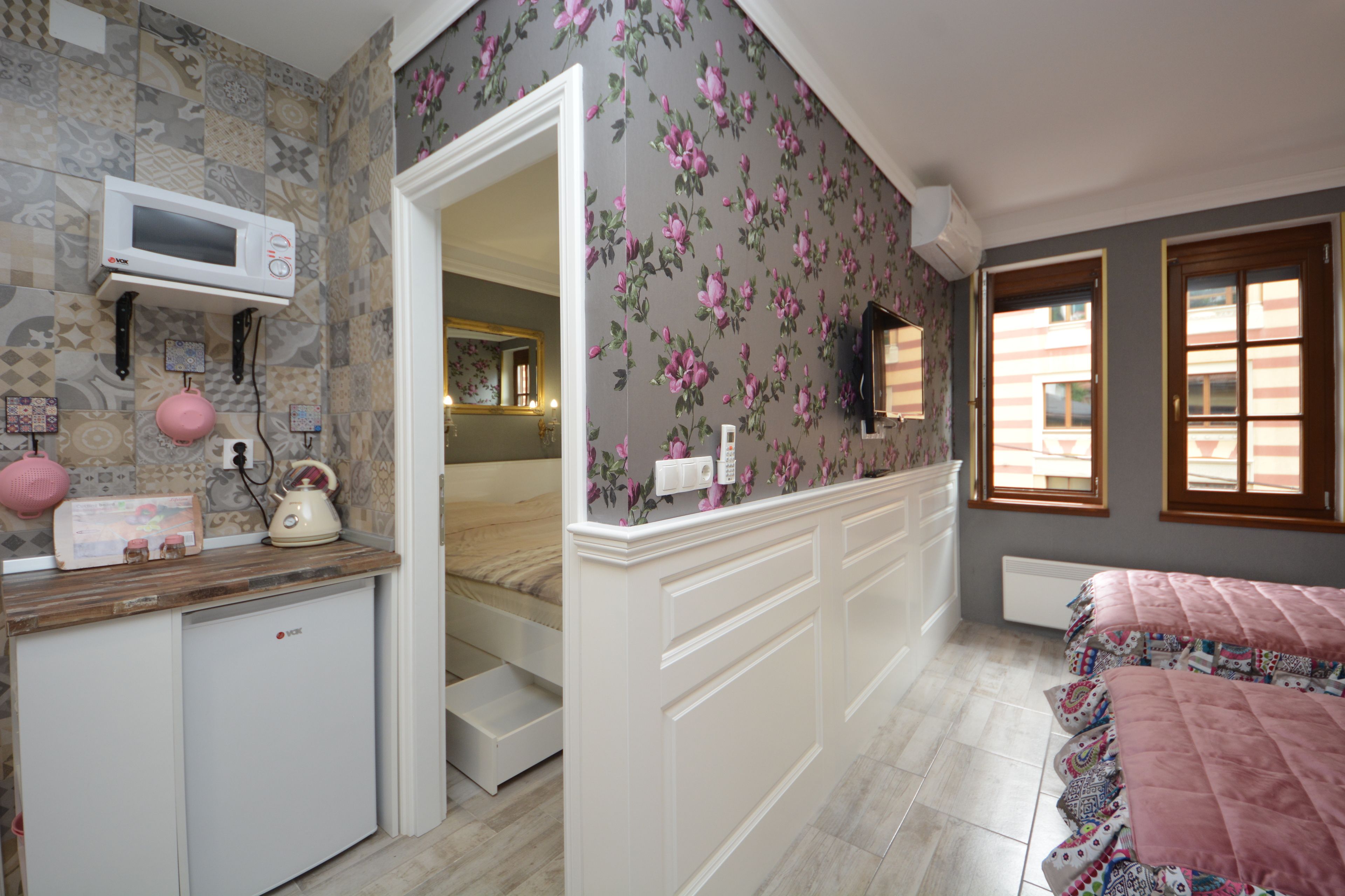 A bedroom with a bed, a dresser, a microwave, and a small kitchenette area.