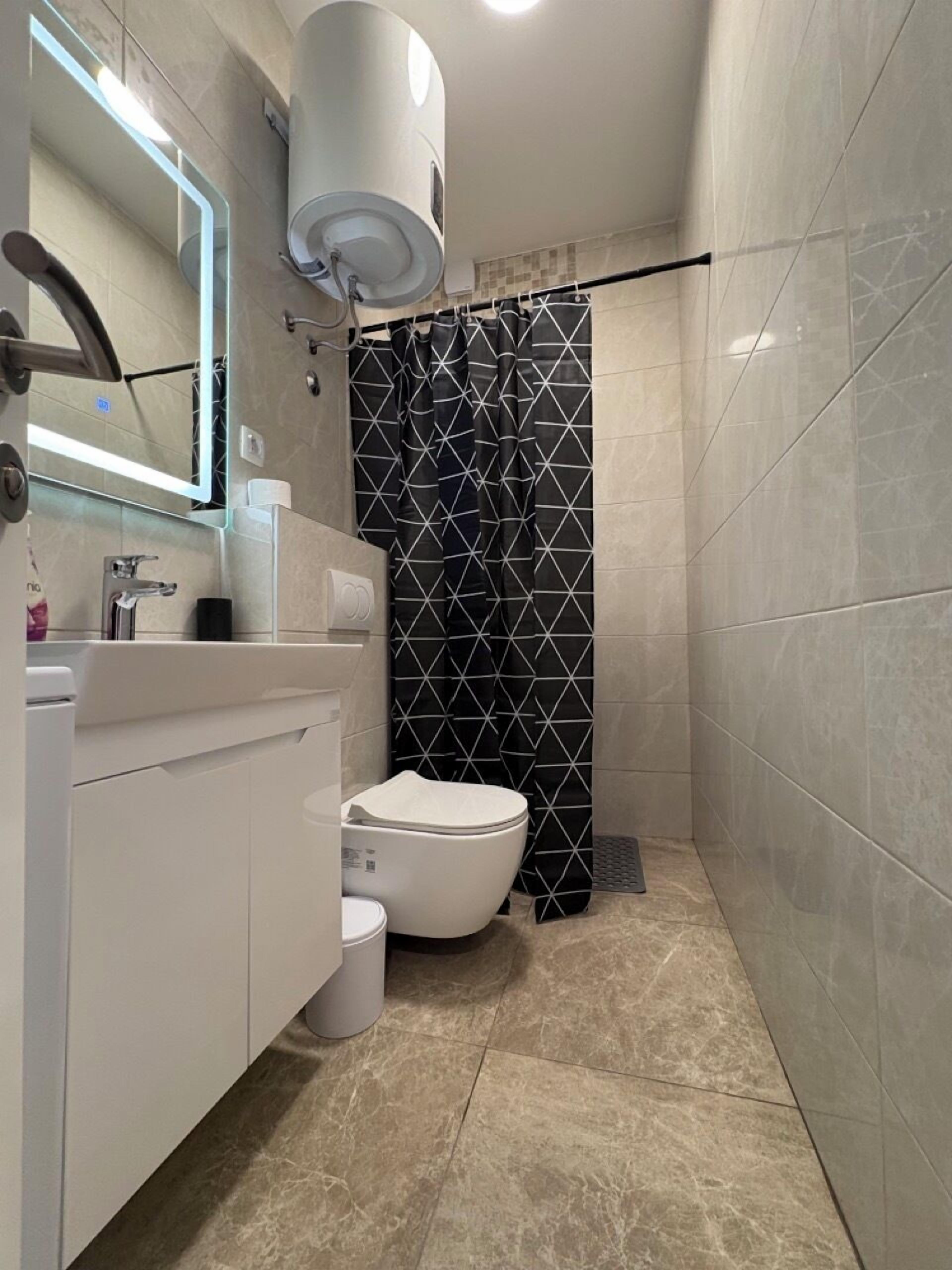 A modern bathroom with a toilet, sink, and mirror.