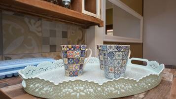 Two patterned cups on a tray, a blue silicone mold, and a decorative doily on a wooden surface.