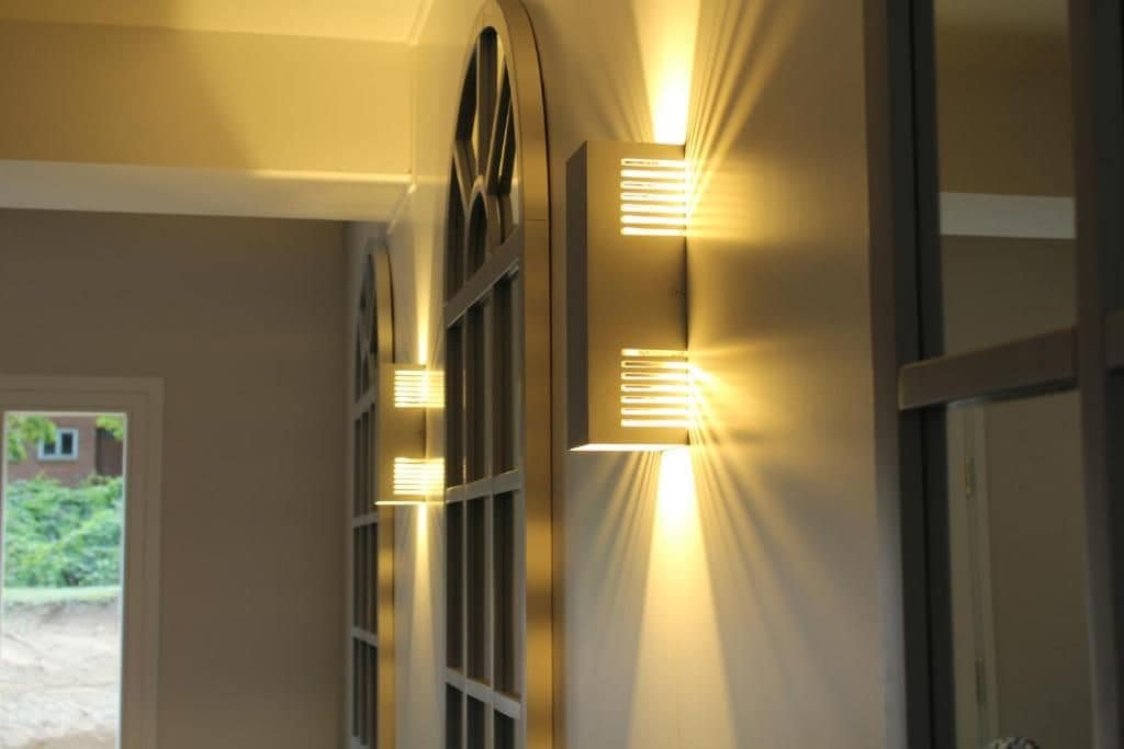 Un pasillo con luces en la pared y una puerta que da al exterior.
