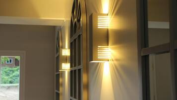 Un pasillo con luces en la pared y una puerta que da al exterior.