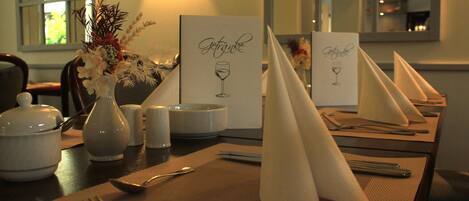 A table set for dining with a vase of flowers, a menu, and a candle.
