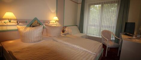 A hotel room with two beds, a desk with a chair, a television, and a window with curtains.