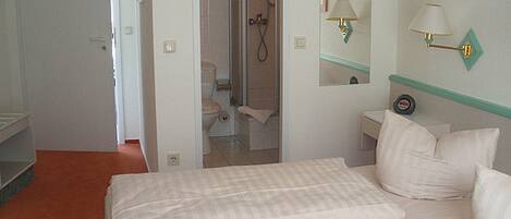 A hotel room with a bed, a bathroom, and a small sitting area.