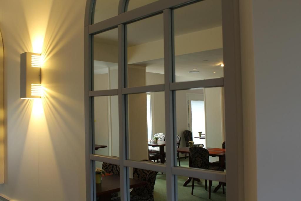 A room with a large window, a dining area with chairs and a table, and a wall-mounted light fixture.