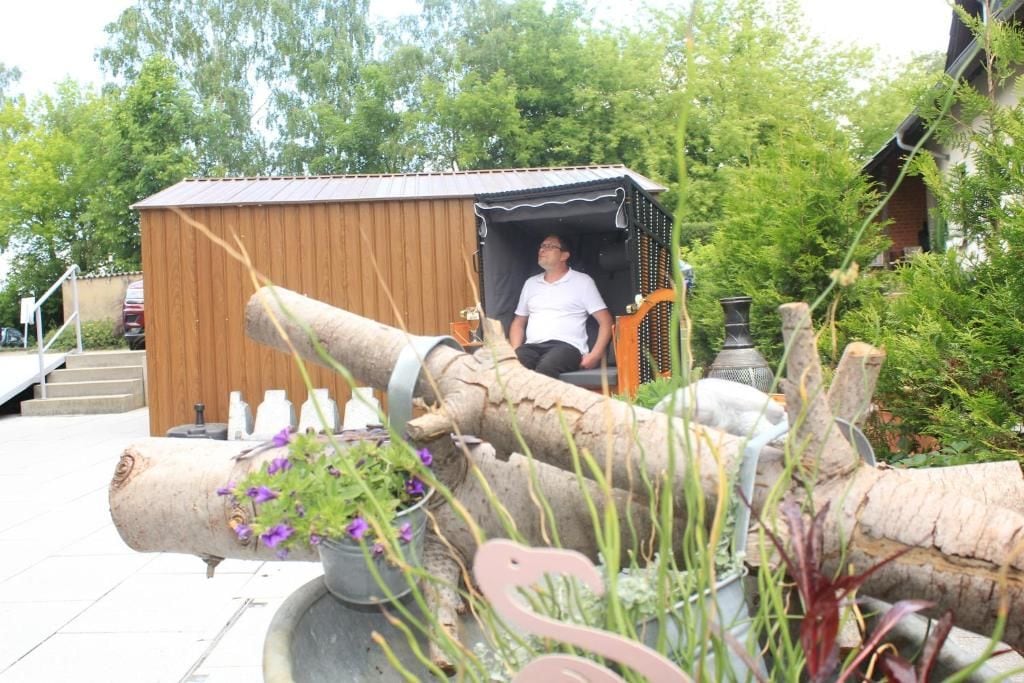 A person sitting on a bench with a wooden structure in the background.