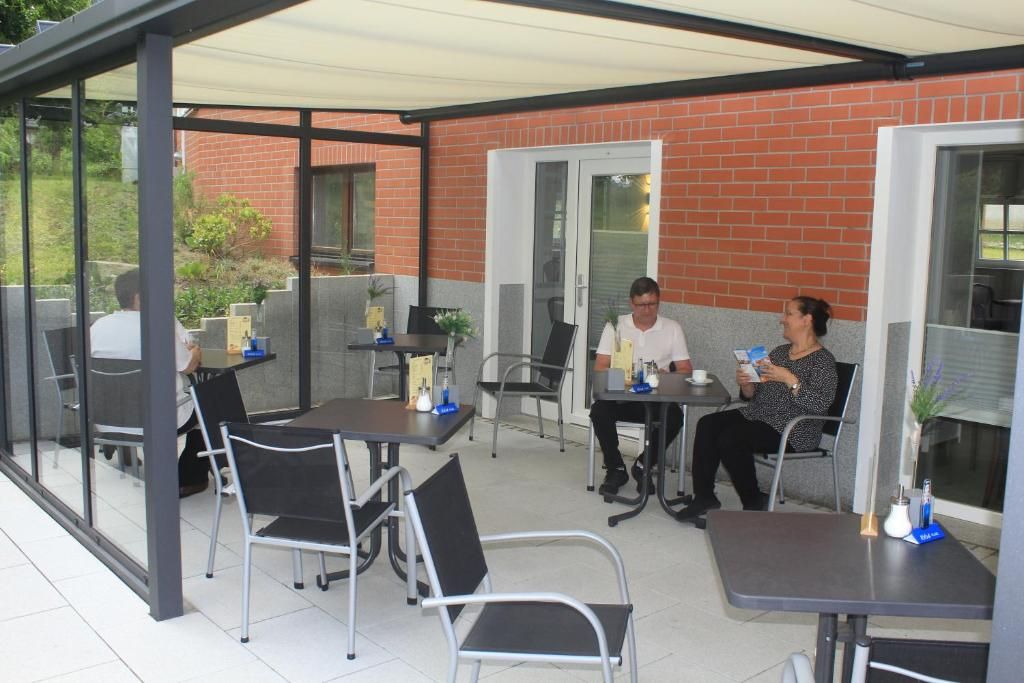 An outdoor patio area with tables and chairs, a brick wall, and a glass door.