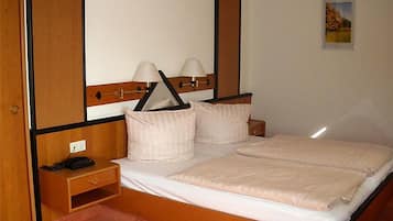 A hotel room with a bed, bedside tables, lamps, and a small picture on the wall.