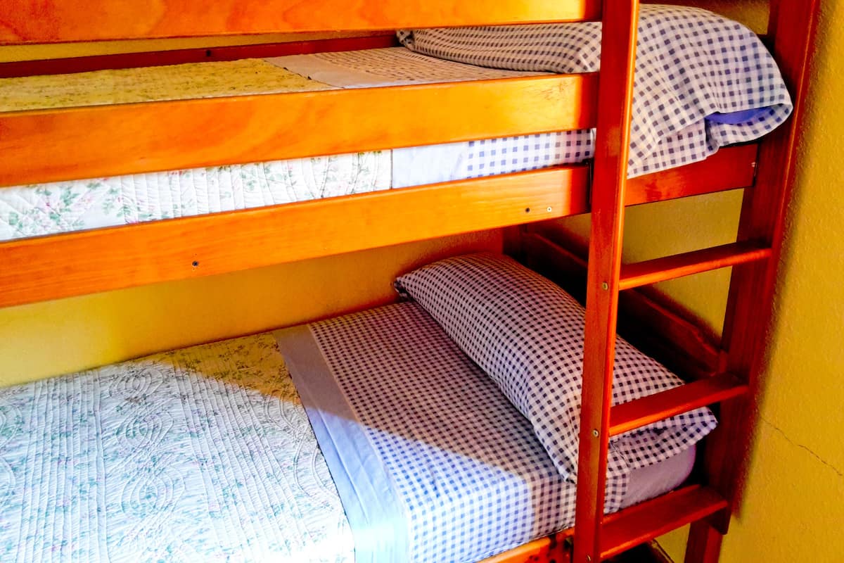 A bunk bed with two levels, each with a mattress and pillow.