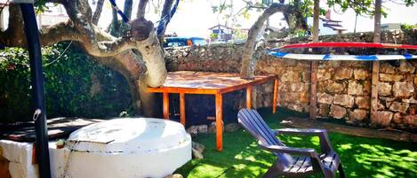 A patio with a table and chairs, surrounded by a stone wall and greenery.