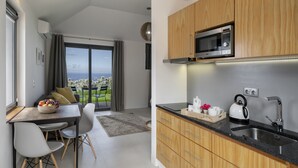 A modern kitchen with wooden cabinets, a built-in microwave, and a kettle on the counter. - Quinta Inácia by Our Madeira (Calheta)