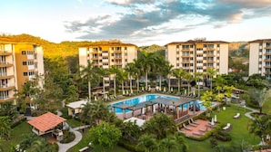 A resort with multiple buildings, a central pool area, and surrounding greenery. - Costa Linda Condo 1.3 (Jacó)