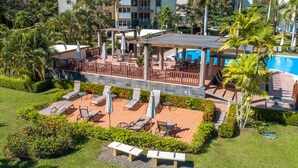 A resort with a pool, outdoor seating, and lush landscaping. - Costa Linda Condo 1.3 (Jacó)