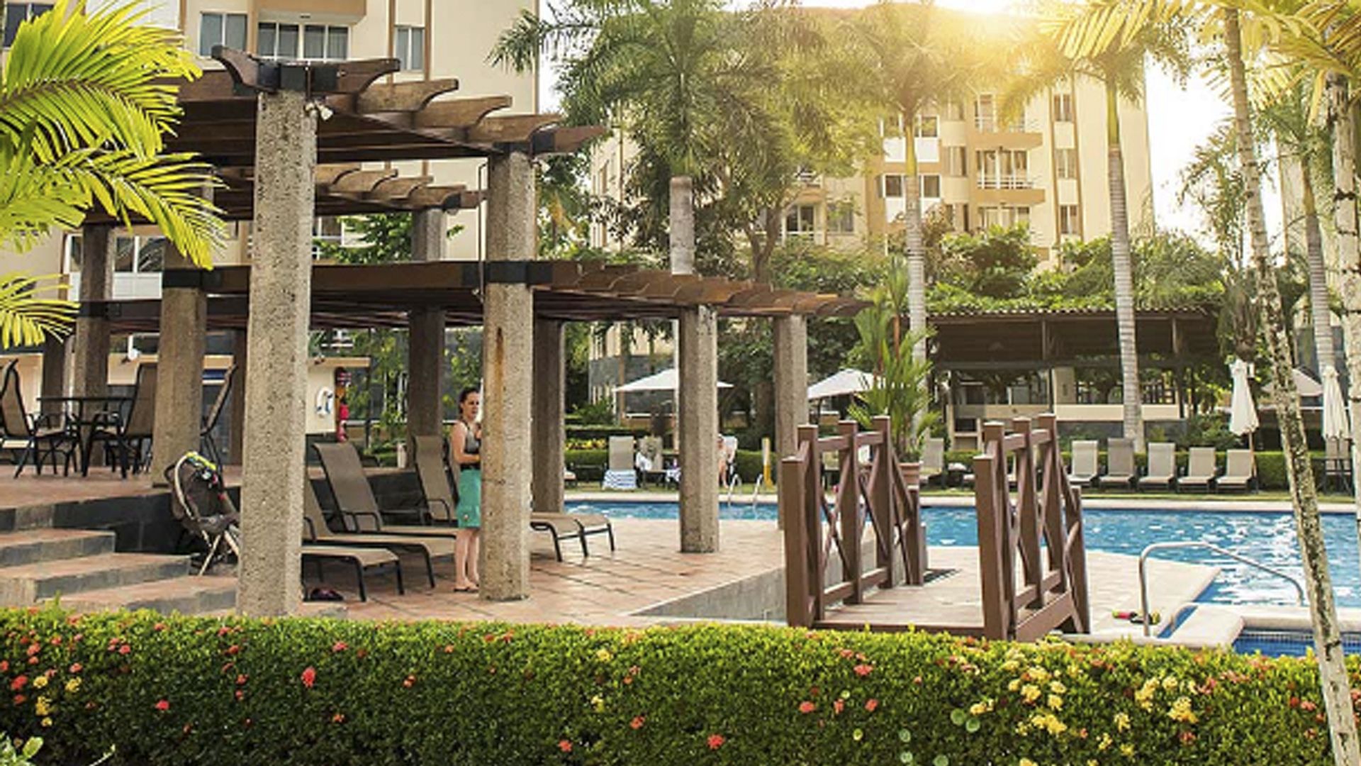 Uma área junto à piscina com espreguiçadeiras, um pérgola e uma piscina.