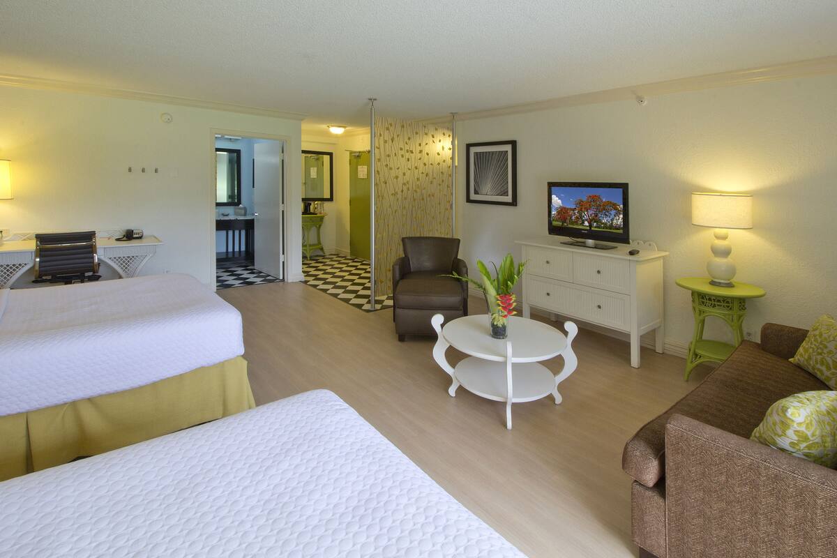 A hotel room with a bed, a sofa, a small table, a TV, and a lamp.
