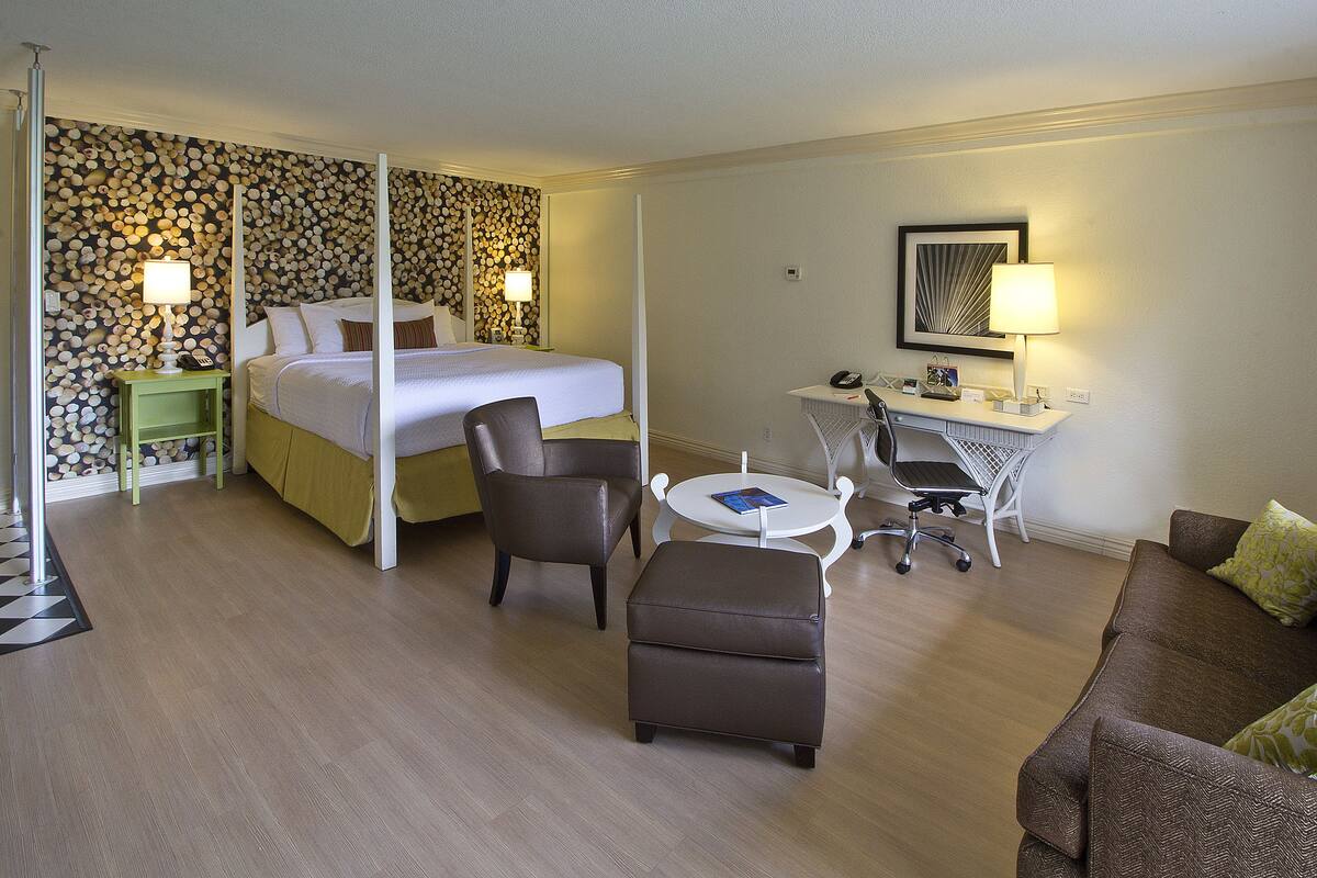 A hotel room with a bed, a desk with a chair, a sofa, and a small table.