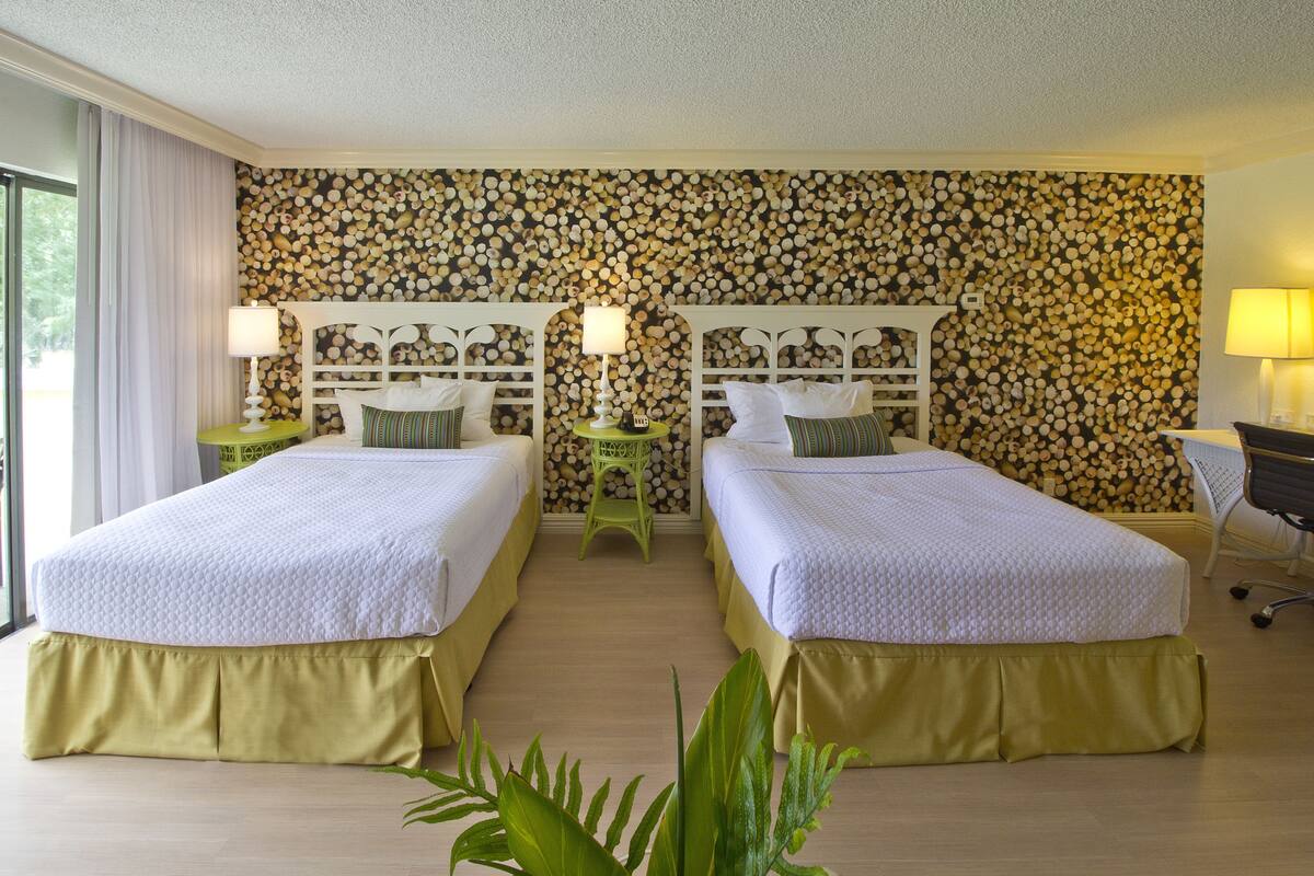 A hotel room with two beds, a wooden log wall, and a view of the outdoors.