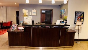 A reception desk with a dark wood finish, three pendant lights, and a framed poster on the wall.