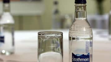 A table with a bottle of Strathmore water and an empty glass.