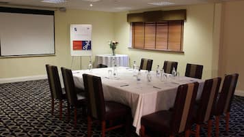 A conference room with a large table, chairs, a flipchart, and a projector.
