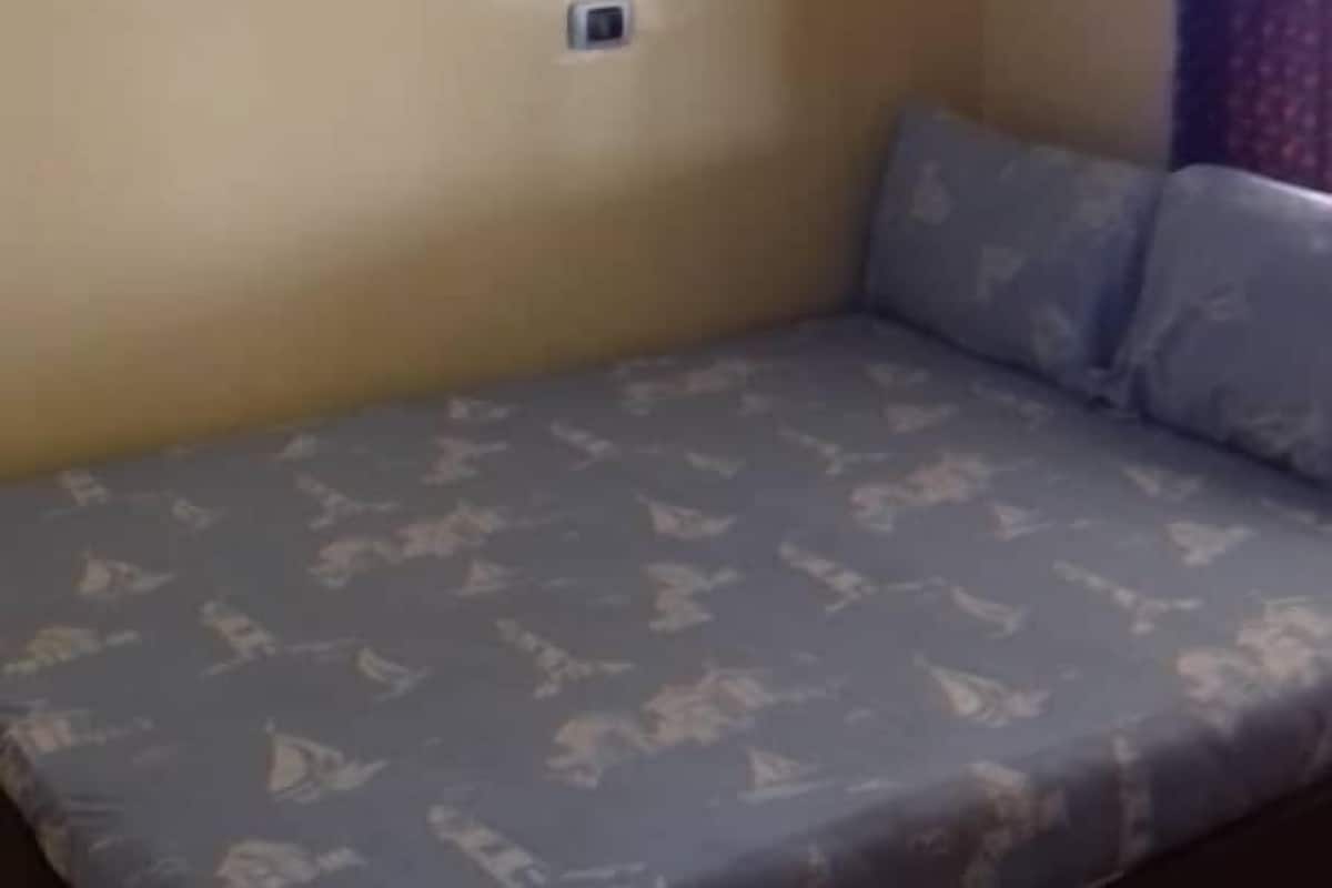Une chambre avec un lit, un climatiseur fixé au mur et une prise de courant.