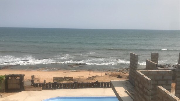 Une vue sur la plage, avec une piscine et des murs en pierre.