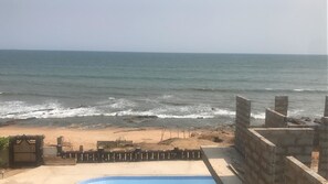 Une vue sur la plage, avec une piscine et des murs en pierre.