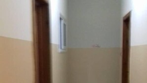 Un couloir étroit, avec un sol carrelé et des murs de couleur beige.