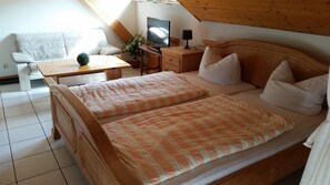Une chambre à coucher avec un lit, des tables de chevet, une télévision et une fenêtre.