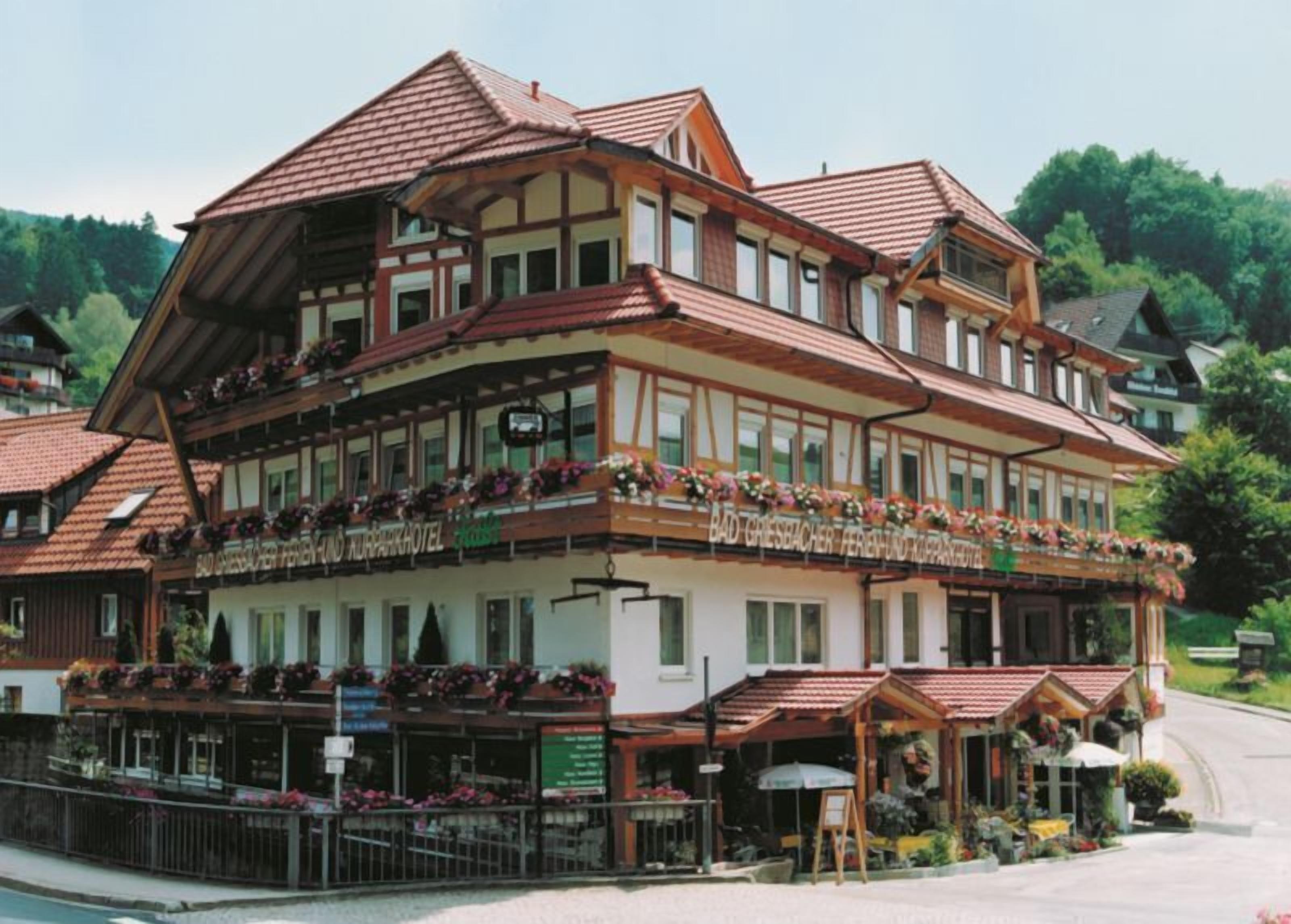A traditional chalet-style hotel with a balcony, wooden facade, and a sign indicating it is a restaurant.