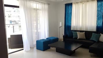 Relax in this stylish living room with a sofa, ottoman, and coffee table, offering a view of the outside through large windows.