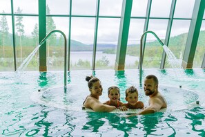 A family in a large indoor swimming pool with a view of a lake and mountains through large windows. - Savalen Fjellhotell & Spa (Tynset)
