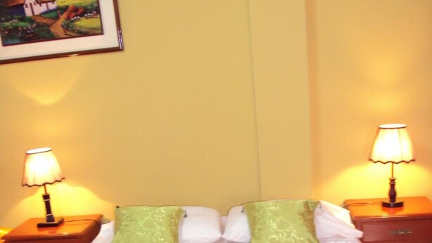 A hotel room with a bed, two nightstands, two lamps, and a framed picture on the wall. - Nasca Lodge (Nazca)