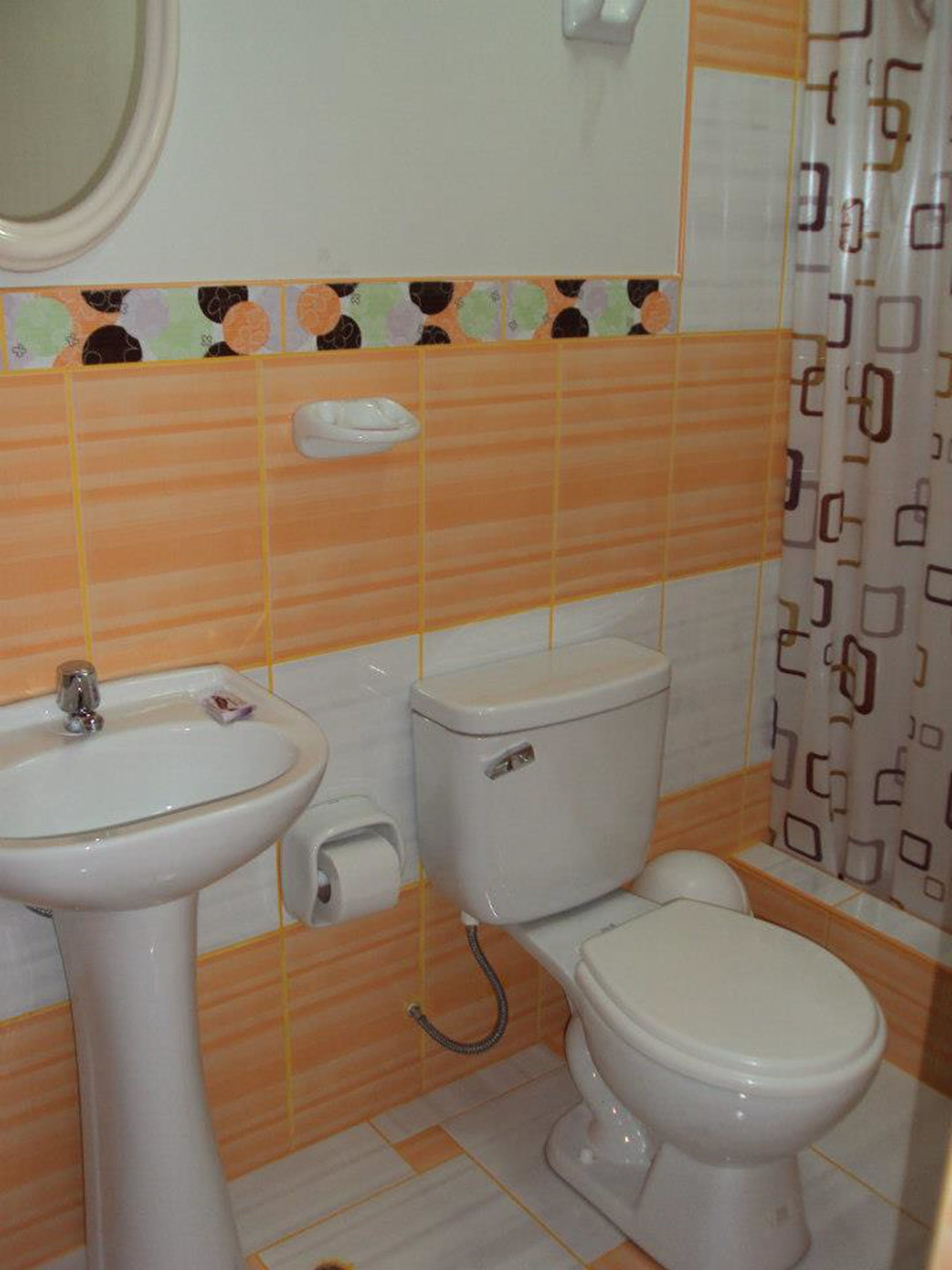 Un baño con lavamanos, inodoro y cortina de ducha.