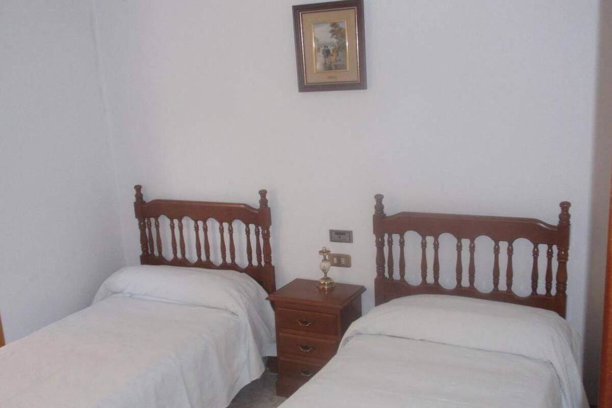A bedroom with two single beds, a wooden nightstand with drawers, and a framed picture on the wall.
