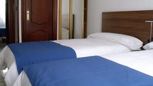 Habitación de hotel con dos camas, cabecero de madera y un espejo.