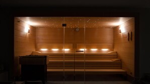 Una sauna con bancos y paredes de madera, equipada con calentadores fijados a la pared y una luz en el techo.
