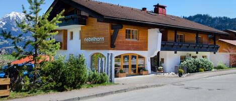A mountain lodge with a prominent '7' sign, wooden exterior, and a view of snow-capped mountains.