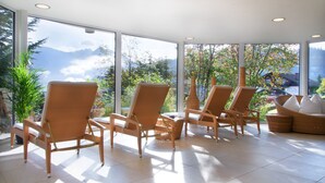 Una habitación luminosa con grandes ventanales, sillas y sofá de mimbre.