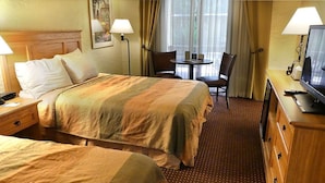 A hotel room with a bed, two chairs, a small table, a TV, and a lamp. - Pima Inn Suites at Talking Stick (Scottsdale)