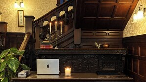 A wooden desk with a laptop, a lit candle, and a potted plant. - Otterburn Castle (Newcastle-upon-Tyne)