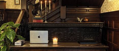 Escritorio de madera con una computadora portátil, una vela encendida y una planta en maceta.