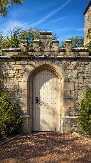 Un arco de piedra que conduce a una puerta de madera con un farol en la pared.