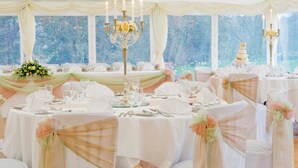 A banquet hall with round tables, white tablecloths, and floral centerpieces. - Otterburn Castle (Newcastle-upon-Tyne)
