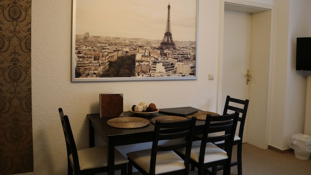 A dining area with a table set for four, a framed cityscape picture on the wall, and a door leading to another room. - Apartment Auenviertel (Erfurt)