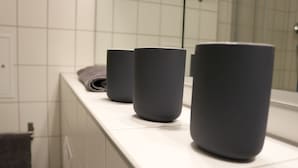 A bathroom with three dark-colored cylindrical containers on a white countertop. - Apartment Auenviertel (Erfurt)