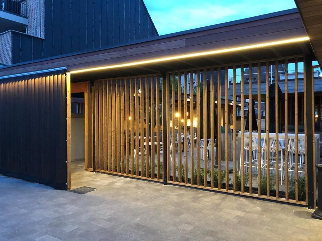 Un edificio moderno con una cerca de madera y un área pavimentada al frente.