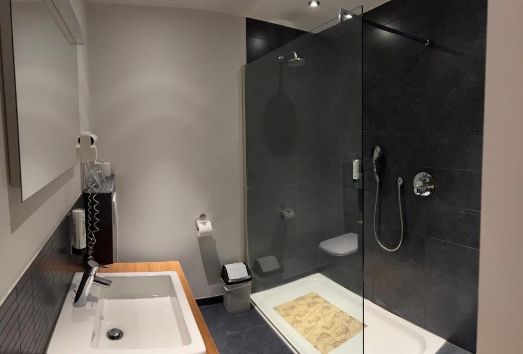 A modern bathroom with a glass-enclosed shower, a sink, and a toilet.